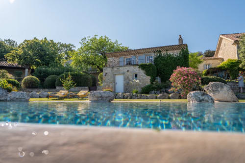 Mas Bella Cortis poolside view in La Garde-Adhémar with stone houses, blooming gardens and clear blue water