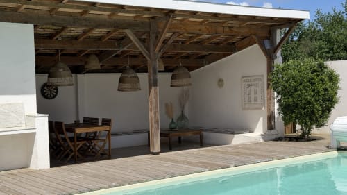Terrasse piscine de la Villa Elara avec pergola bois, luminaires suspendus tressés, coin repas et piscine turquoise à Mimizan