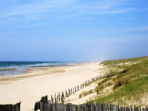 Plage de sable avec dunes et clôture côtière à Mimizan, Landes, idéale pour une escapade en villa balnéaire