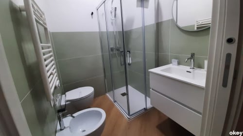 Bagno moderno con piastrelle verdi, doccia, water, bidet e lavabo nella camera dell'hotel Bari Centro