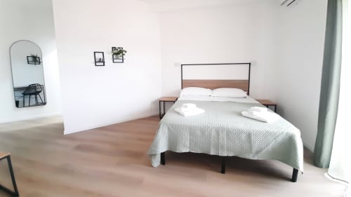 Camera moderna del B&B Bari Centro con letto matrimoniale, pavimenti in legno, arredamento minimalista e vista sulla città di Bari
