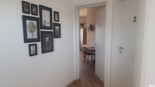 Corridoio con quadri botanici incorniciati che conducono alle camere del B&B Bari Centro, porte numerate visibili