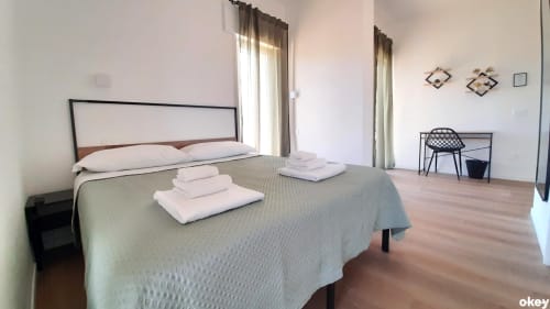 Camera da letto moderna e spaziosa al B&B Bari Centro con letto matrimoniale, asciugamani bianchi, pavimenti in legno e luce naturale dalle ampie finestre