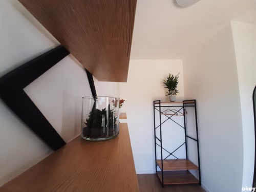 Camera moderna del B&B di Bari con mobili in legno, pianta in vaso e scaffalatura metallica vicino alle pareti bianche