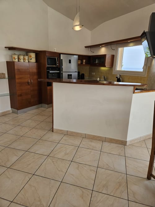 Cuisine moderne équipée avec meubles en bois, appareils en acier inoxydable et carrelage à la Villa Eva gérée par la conciergerie Corsu Di Core