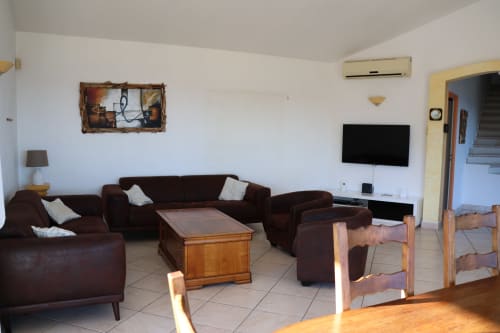 Spacieux séjour de la Villa Eva géré par la conciergerie Corsu Di Core, Solenzara, avec sièges marron, table en bois, TV écran plat et design moderne