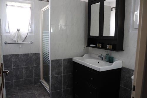 Salle de bains moderne à la Villa Eva gérée par la conciergerie Corsu Di Core avec vanité noire, lavabo blanc et douche carrelée foncée