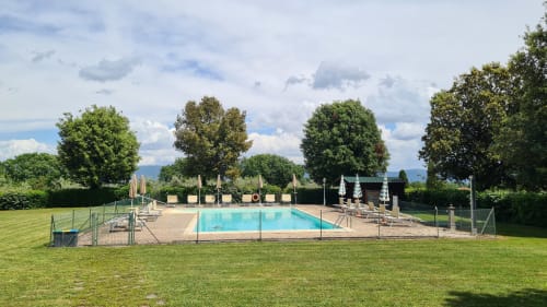 Piscina della struttura con sdraio e ombrelloni circondata da giardini rigogliosi presso l'Agriturismo Buriano a Lubriano, Italia