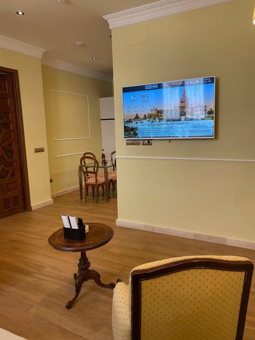 Elegant living room at Edificio San Esteban 16 in Sevilla with yellow walls, flat-screen TV displaying city landmarks, wooden