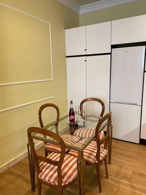 Modern Seville apartment dining area with wooden chairs, glass table, and white kitchen cabinetry