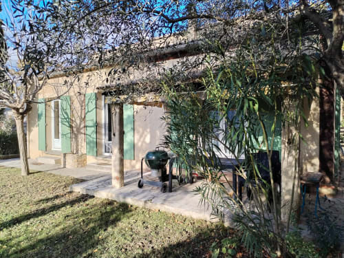 Encantador patio de casa rural francesa con persianas verdes, vides desnudas y parrilla en Gagnières