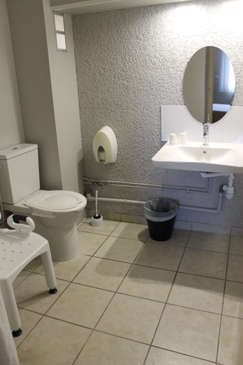 Salle de bains accessible à Libre Hôtel : toilettes, lavabo, miroir et barres de maintien pour accès fauteuil roulant