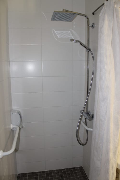 Salle de bains accessible avec pomme de douche pluie et douchette à main à la chambre PMR de Libre Hôtel à La Vespière