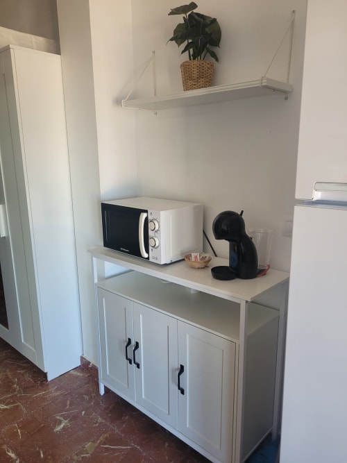 Pequeña cocina blanca con microondas y cafetera en Apartamentos A la Orilla del Mar, Matalascañas