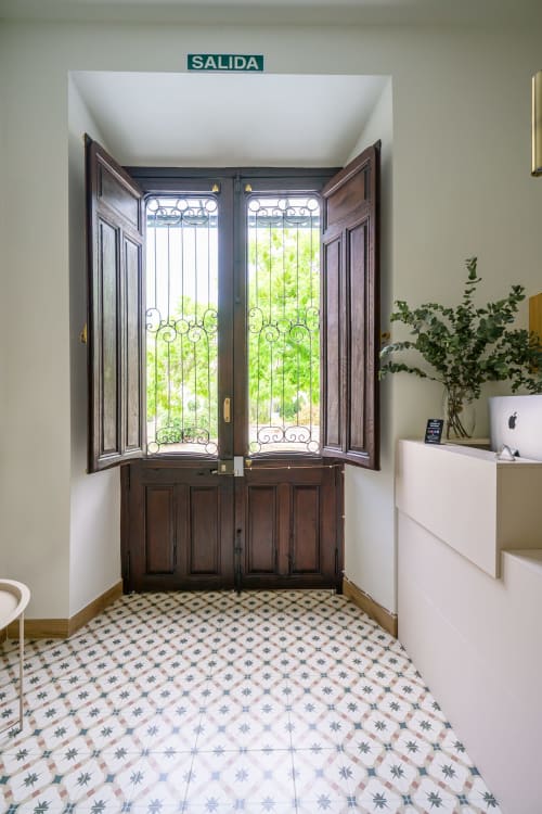 Pasillo de salida del Hotel Boutique Alcazaba en Salobreña con puertas de madera oscura, ventanas decorativas y suelo de baldosas con patrón