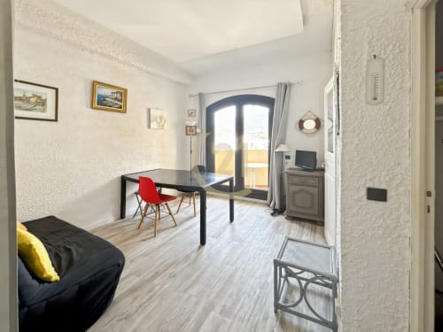 Séjour moderne d'un T3 à L'Île-Rousse avec vue mer, table à manger, chaise rouge et accès à la terrasse