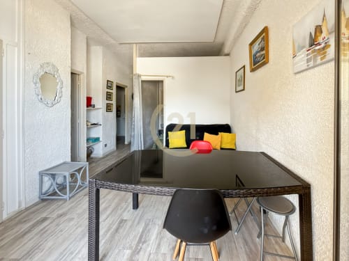 Appartement T3 moderne à L'Île-Rousse avec table à manger noire, coussins jaunes, miroir et décoration côtière
