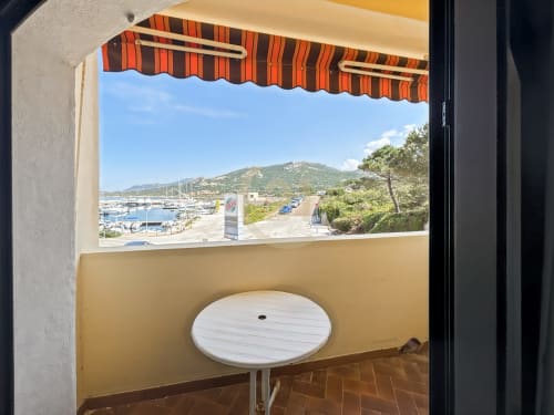 Terrasse en bord de mer avec auvent rayé surplombant la marina et les montagnes, appartement à L'Île-Rousse avec vue sur mer