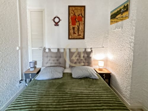 Chambre cosy avec literie verte rayée et tête de lit taupe dans l'appartement L'Île-Rousse avec vue mer et accès au port