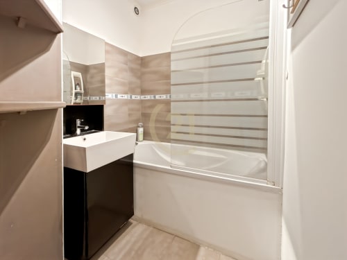 Salle de bain moderne de l'appartement L'Île-Rousse avec baignoire blanche, carrelage mural rayé et meuble vasque noir