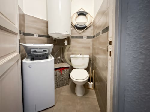 Salle de bain compacte avec lave-linge et toilettes dans un appartement Century 21, L'Île-Rousse, Corse