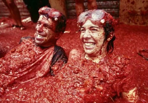 Deux clients couverts de pulpe de tomate rouge riant à l'hôtel Casa Sibarita à Rafelguaraf, Espagne