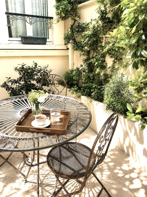 Charmante cour intérieure de l'Hôtel des Bains avec table métallique ornementale, chaises, service à café et lierre grimpant