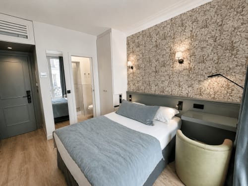 Chambre moderne à l'Hôtel des Bains avec lit queen-size, papier peint à motifs et accès à la salle de bain privée