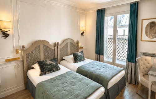 Chambre twin à l'Hôtel des Bains avec rideaux turquoise, têtes de lit élégantes et vue sur les balcons parisiens