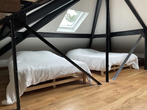 Modern loft bedroom with black metal canopy beds, white bedding, wooden floors, and skylight in Villa Sonneville suite.
