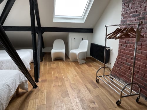Modern attic bedroom at Villa Sonneville B&B in Roubaix with exposed beams, skylight, wooden floors and seating area
