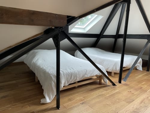 Modern attic bedroom at Villa Sonneville with skylight, white bedding, black metal canopy bed frame, wooden beams, and