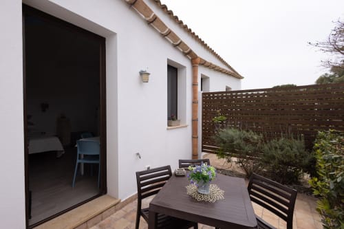 Outdoor dining terrace at Senia del Rais in Favignana with table, chairs, potted flowers, and wooden privacy fence
