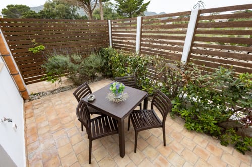 Private outdoor dining area at Senia del Rais in Favignana with table, chairs, and Mediterranean plants behind wooden privacy