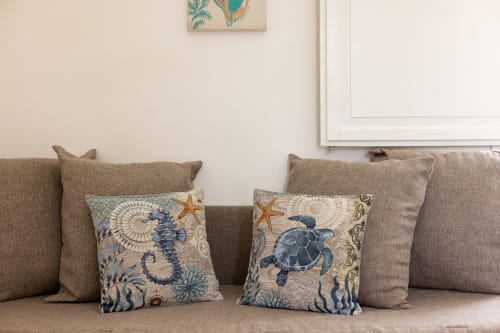 Beige sofa with nautical throw pillows featuring seahorse and sea turtle designs in Cavaluccio Marino room at Senia del Rais,