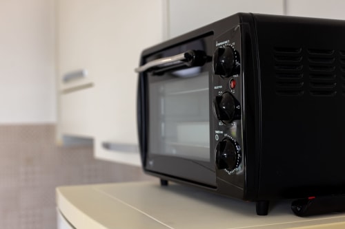 Black compact oven with control dials in Cavaluccio Marino room at Senia del Rais, Favignana