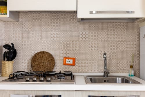 Modern kitchen with beige patterned backsplash, gas cooktop, and stainless steel sink at Senia del Rais, Favignana
