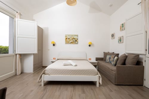 Bright bedroom in Cavaluccio Marino room at Senia del Rais B&B in Favignana with bed, sofa, and ocean view window