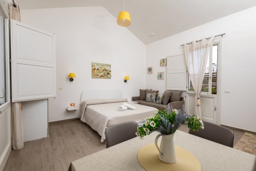 Bright bedroom at Senia del Rais in Favignana with bed, sofa, yellow accents, and ocean view doors