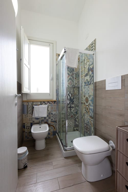 Modern bathroom at Senia del Rais in Favignana with shower, bidet, toilet, and decorative blue tilework