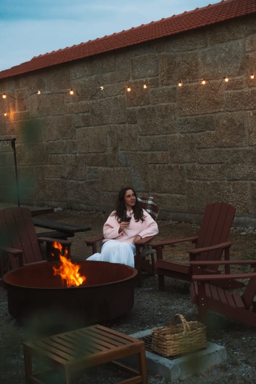 Woman enjoying evening by fire pit at Canhoto Douro in São Lourenço do Douro, Portugal