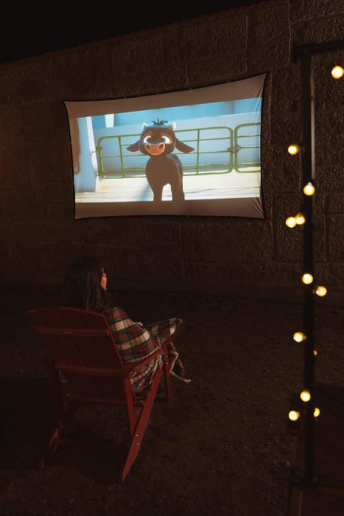Guest watching animated film on outdoor projection screen at Canhoto Douro guesthouse in São Lourenço do Douro
