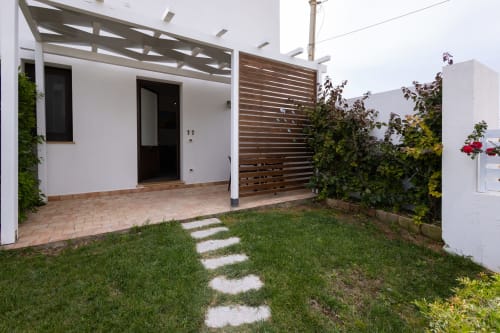 Medusa apartment garden view at Senia del Rais, Favignana - patio with pergola, stepping stones, and lush landscaping