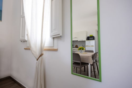 Mirror reflecting Medusa apartment kitchen and dining area at Senia del Rais in Favignana with white cabinetry and dining