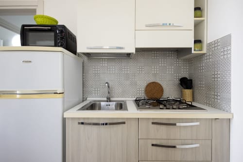 Modern kitchenette in Medusa apartment at Senia del Rais, Favignana, with gas stove, sink, and geometric tile backsplash