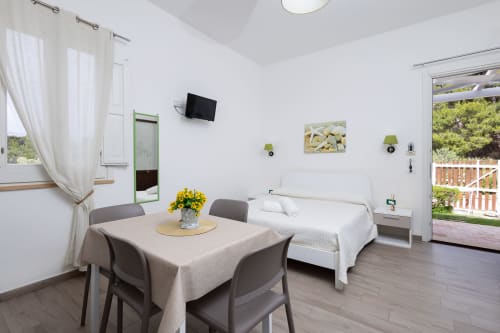 Medusa apartment at Senia del Rais in Favignana with bed, dining table, TV, and garden view from balcony