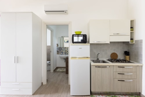 Modern kitchen in Medusa apartment at Senia del Rais, Favignana with white cabinetry, stove, refrigerator and tiled