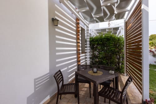 Outdoor dining area in Medusa apartment at Senia del Rais, Favignana, with louvered pergola providing shade and privacy