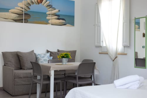 Medusa apartment at Senia del Rais in Favignana features a cozy seating area with sofa, dining table, and sea-themed wall art
