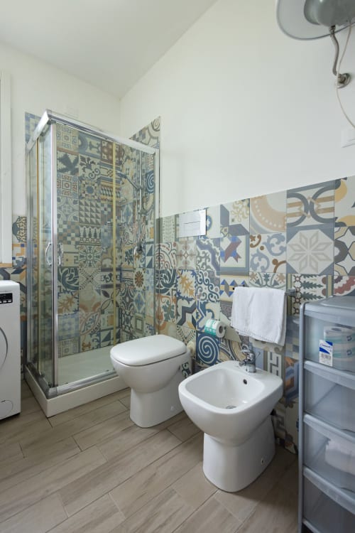Modern bathroom in Stella Marina room at Senia del Rais, Favignana with patterned tile walls, shower enclosure, toilet and